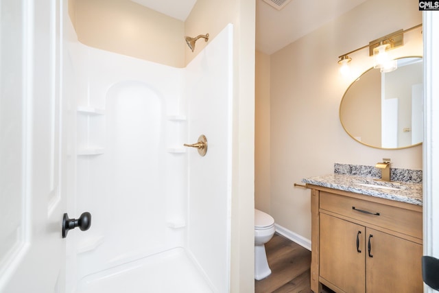 bathroom with vanity, a shower, hardwood / wood-style floors, and toilet