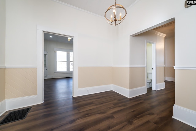 unfurnished room with crown molding, dark hardwood / wood-style floors, and a chandelier