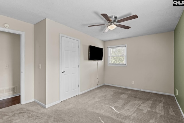 unfurnished bedroom with ceiling fan, light colored carpet, and a textured ceiling