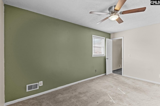 unfurnished room featuring ceiling fan, light colored carpet, and a textured ceiling