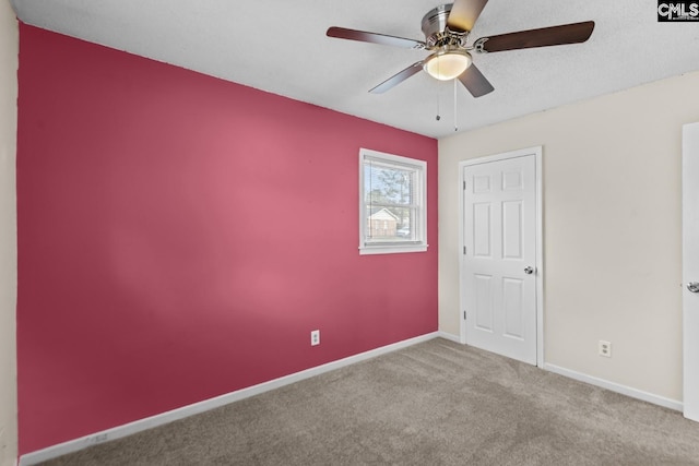 carpeted empty room featuring ceiling fan and a textured ceiling