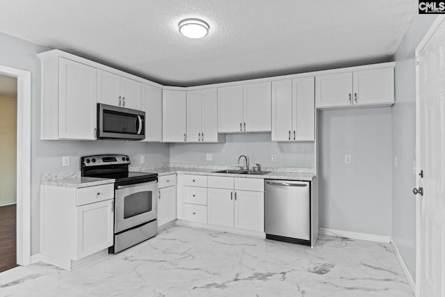 kitchen with stainless steel appliances, sink, white cabinets, and a textured ceiling