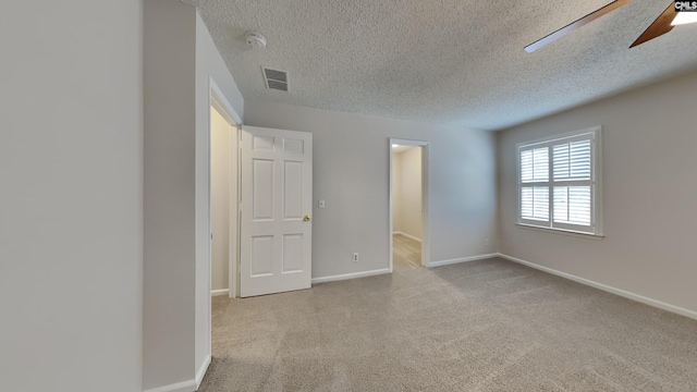 carpeted spare room with ceiling fan and a textured ceiling