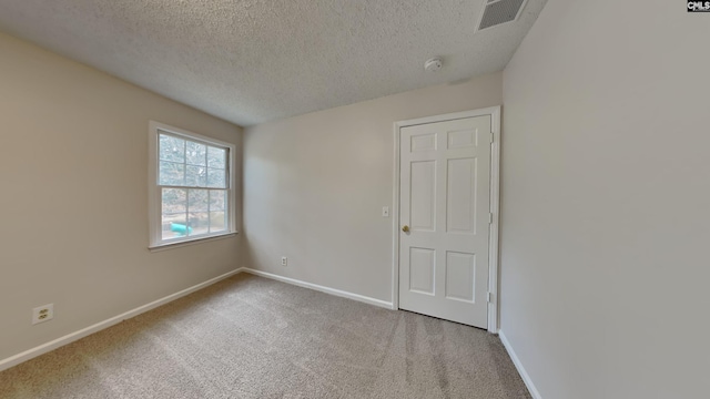 carpeted empty room with a textured ceiling