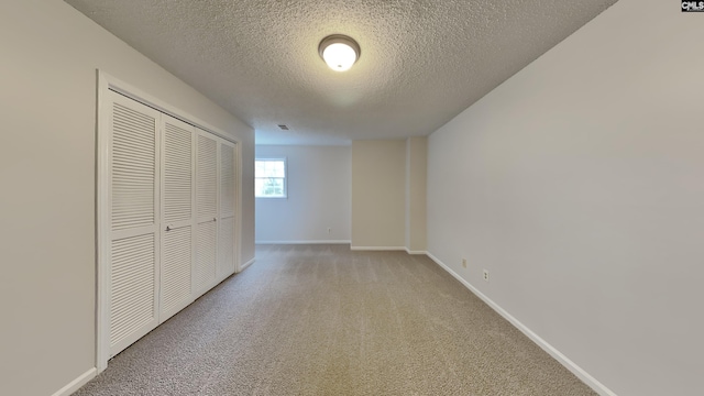 unfurnished bedroom featuring light colored carpet, a closet, and a textured ceiling