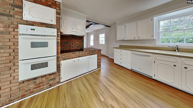 kitchen featuring sink, white appliances, white cabinets, brick wall, and light wood-type flooring