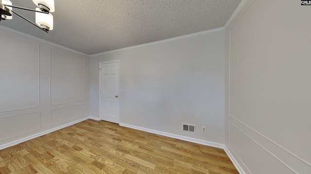 empty room featuring light hardwood / wood-style flooring, ornamental molding, and a textured ceiling