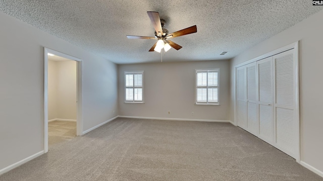 unfurnished bedroom featuring ceiling fan, light carpet, a textured ceiling, and a closet