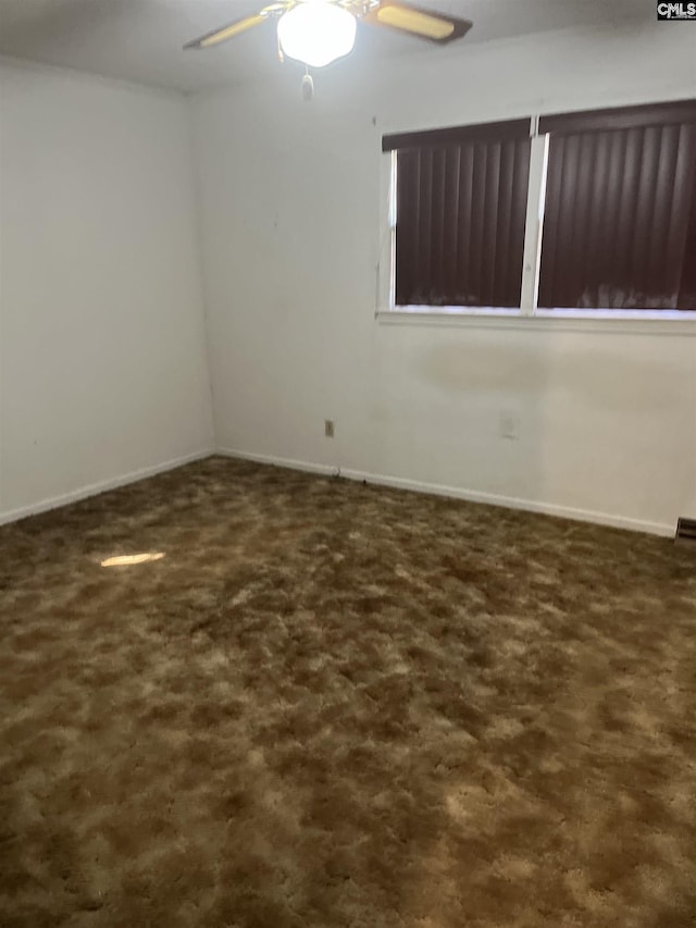 spare room featuring dark colored carpet and ceiling fan