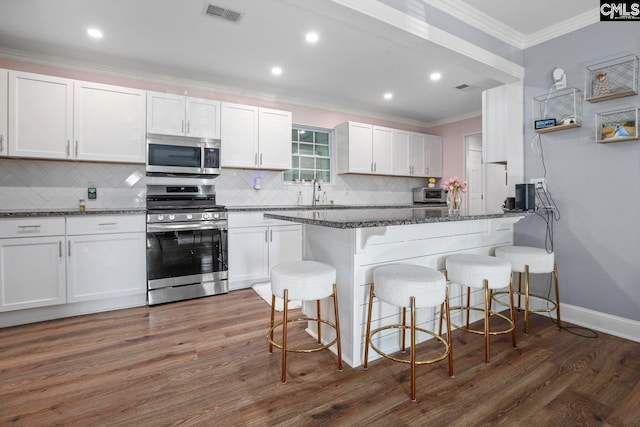 kitchen featuring dark stone counters, white cabinets, and appliances with stainless steel finishes