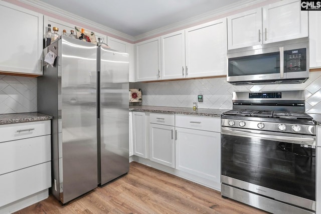 kitchen featuring white cabinetry, appliances with stainless steel finishes, dark stone countertops, and light wood-type flooring