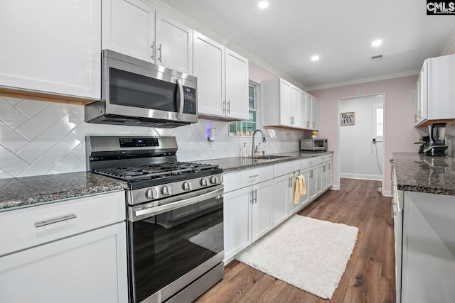 kitchen with stainless steel appliances, white cabinetry, ornamental molding, and sink