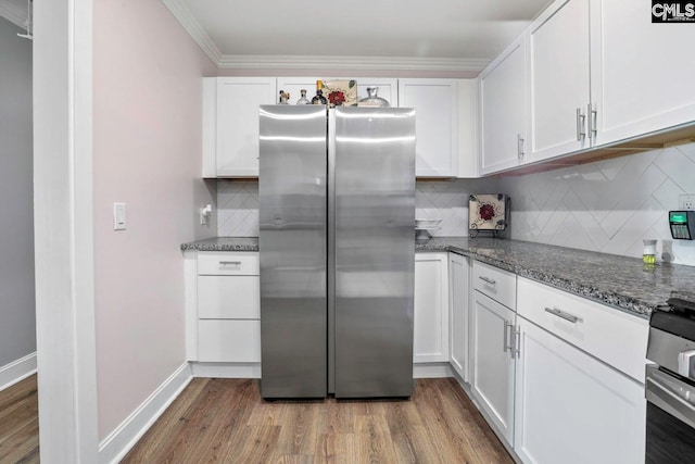 kitchen with stainless steel refrigerator, dark stone counters, wood-type flooring, and white cabinets