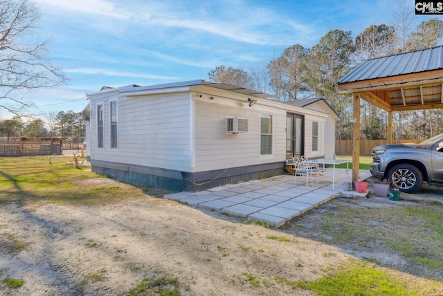 view of side of home with a yard, a wall unit AC, and a patio area