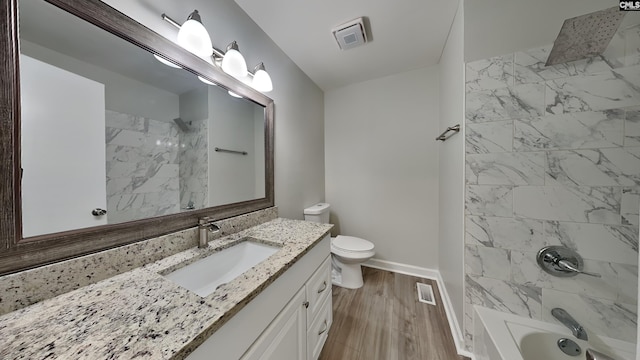 full bathroom with hardwood / wood-style flooring, tiled shower / bath, vanity, and toilet