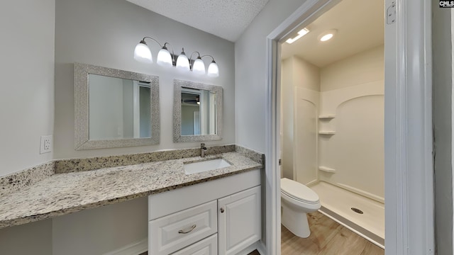 bathroom with hardwood / wood-style flooring, vanity, walk in shower, toilet, and a textured ceiling