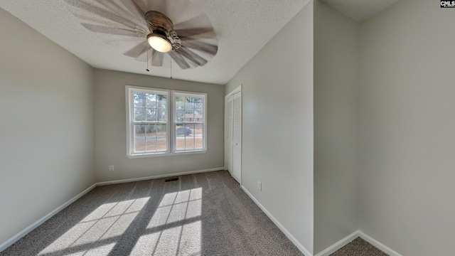 carpeted spare room featuring ceiling fan and a textured ceiling