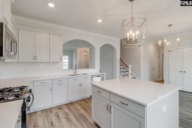 kitchen featuring ornamental molding, appliances with stainless steel finishes, light wood-type flooring, and a sink