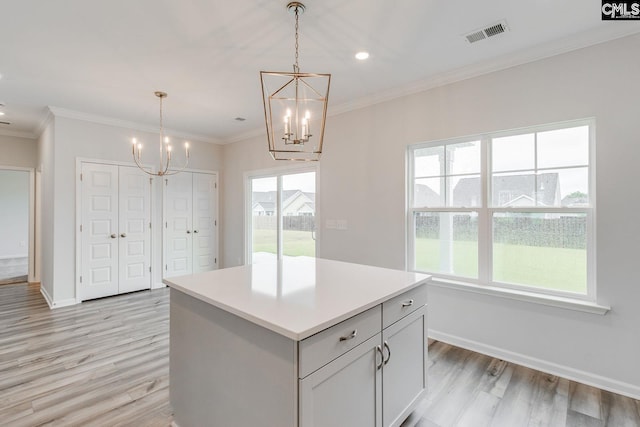 kitchen featuring light wood-style flooring, visible vents, crown molding, and a center island