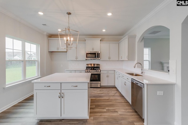 kitchen featuring visible vents, light wood-style flooring, ornamental molding, stainless steel appliances, and a sink