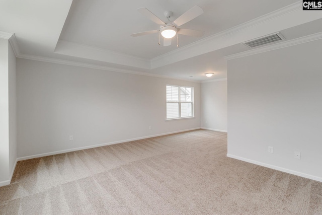 carpeted spare room with a raised ceiling, visible vents, crown molding, and baseboards