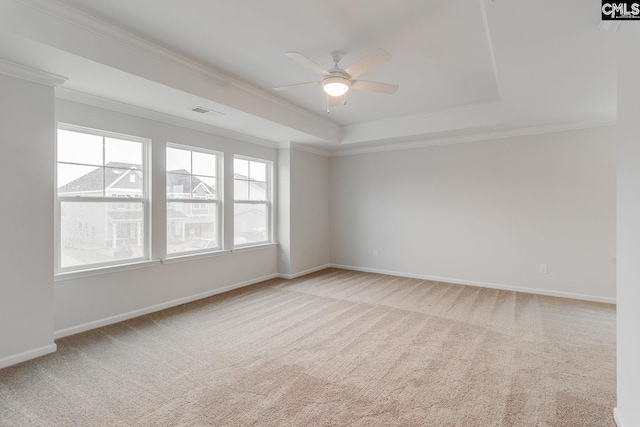 empty room with ornamental molding, carpet, a raised ceiling, and visible vents