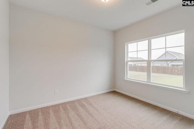 spare room with baseboards, visible vents, and light colored carpet