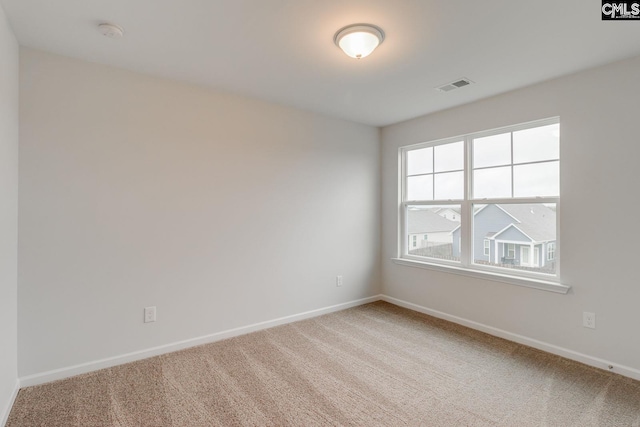 spare room featuring light carpet, visible vents, and baseboards