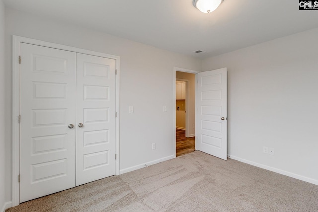 unfurnished bedroom with a closet, carpet flooring, and baseboards