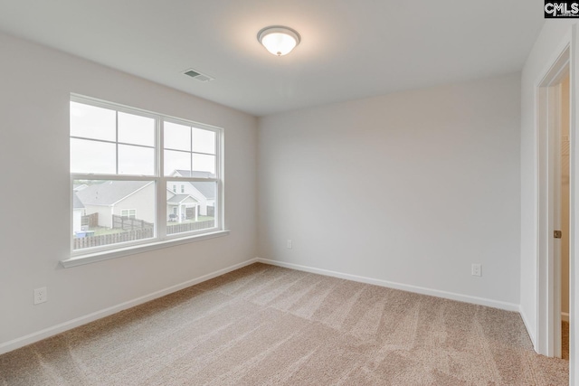 spare room with carpet flooring, visible vents, and baseboards