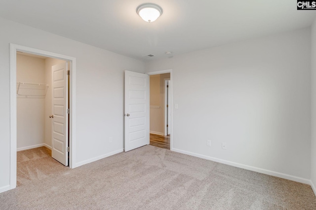 unfurnished bedroom featuring carpet, a spacious closet, and baseboards