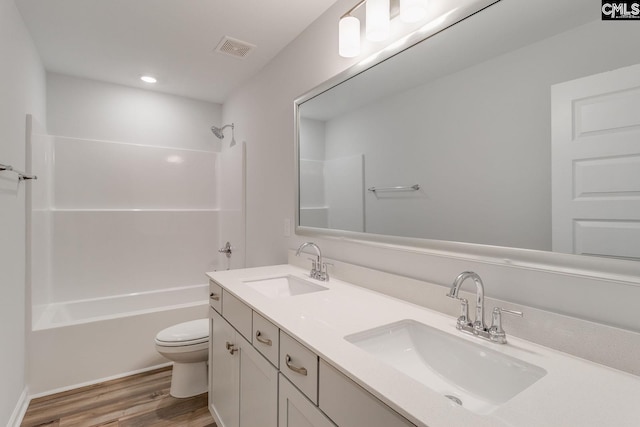 bathroom featuring toilet, shower / bath combination, a sink, and wood finished floors