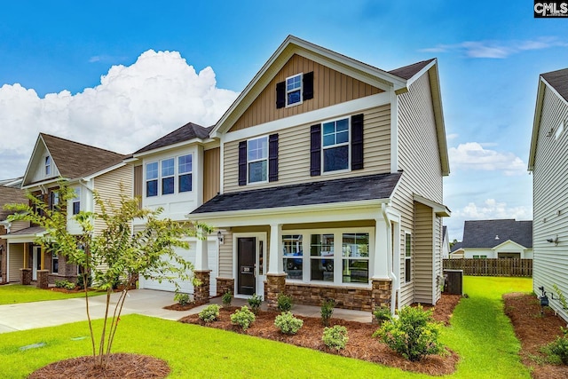 craftsman inspired home with concrete driveway, board and batten siding, a front yard, fence, and stone siding