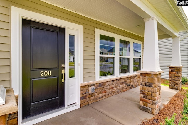 entrance to property featuring a porch and stone siding