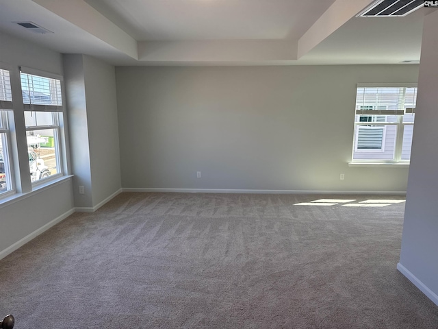 spare room featuring carpet floors, visible vents, plenty of natural light, and baseboards