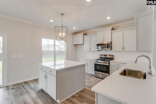 kitchen with a sink, light countertops, appliances with stainless steel finishes, tasteful backsplash, and crown molding