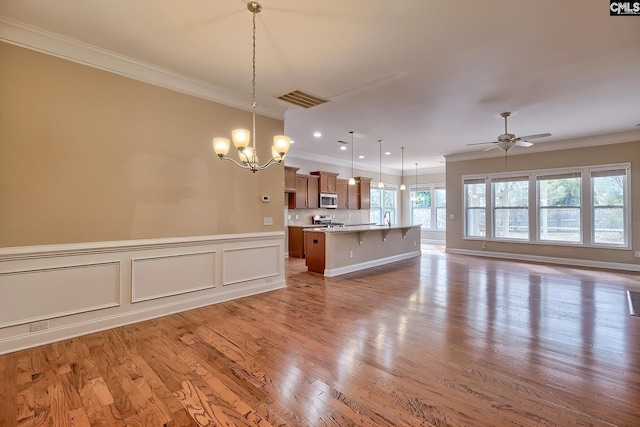 kitchen featuring pendant lighting, crown molding, a kitchen breakfast bar, and a center island