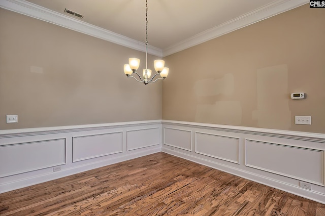 unfurnished room with hardwood / wood-style flooring, ornamental molding, and an inviting chandelier