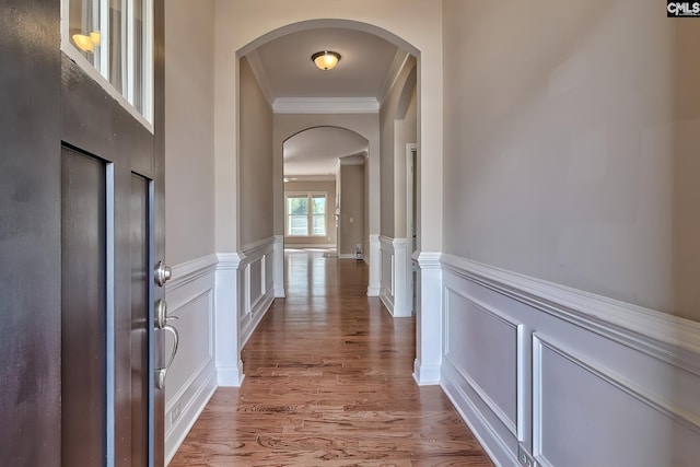 corridor with ornamental molding and hardwood / wood-style floors