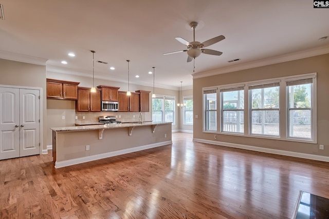 kitchen with a breakfast bar, hanging light fixtures, light stone counters, stainless steel appliances, and light wood-type flooring