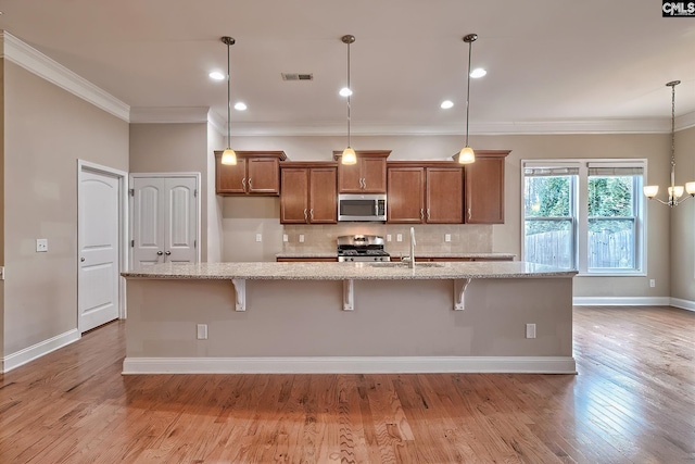 kitchen featuring light stone counters, appliances with stainless steel finishes, a kitchen breakfast bar, and a center island with sink