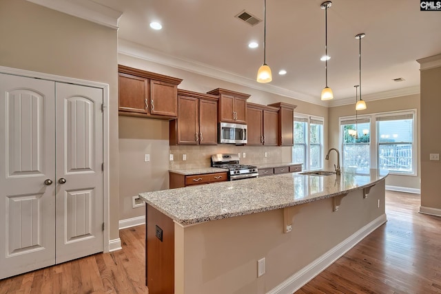 kitchen featuring hanging light fixtures, an island with sink, appliances with stainless steel finishes, and sink