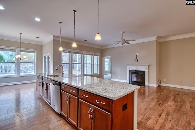 kitchen with sink, hanging light fixtures, a center island with sink, dishwasher, and light stone countertops