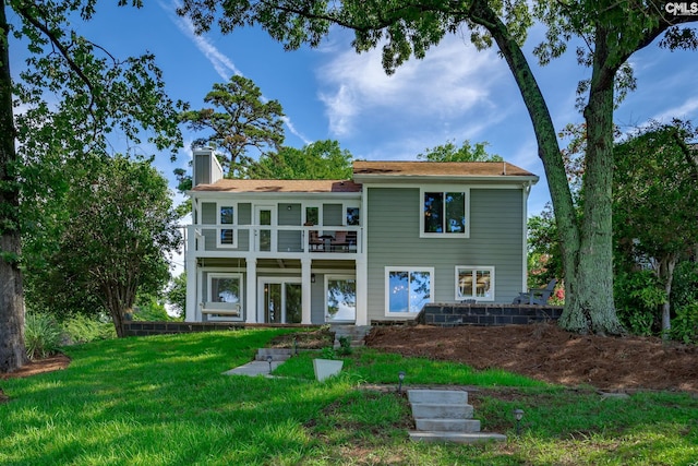 rear view of house featuring a balcony and a yard