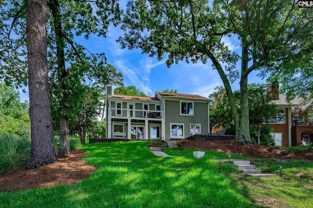 back of house with a balcony and a lawn