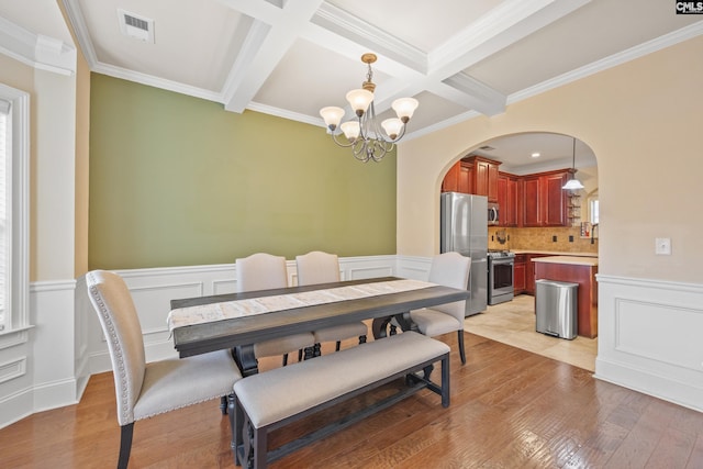 dining area featuring beamed ceiling, an inviting chandelier, and light wood-type flooring