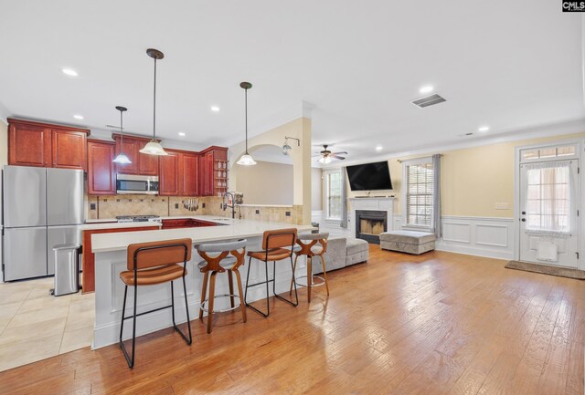 kitchen with a breakfast bar, sink, appliances with stainless steel finishes, kitchen peninsula, and pendant lighting