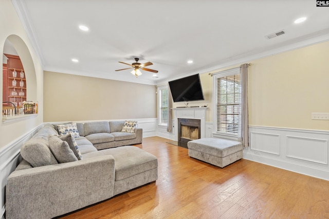 living room featuring wood-type flooring, ornamental molding, and ceiling fan