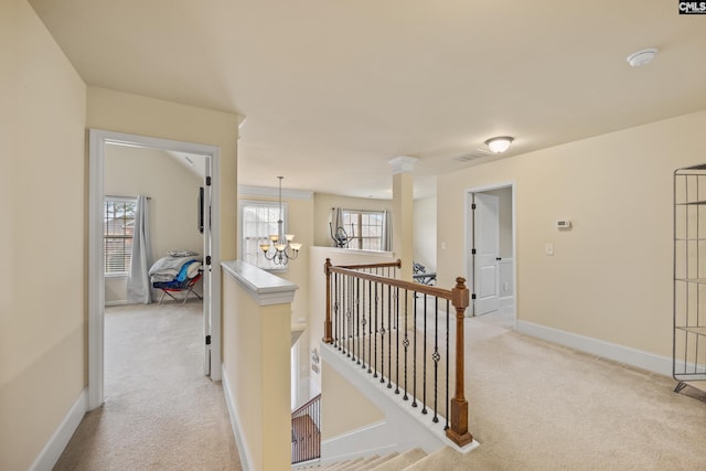 hall featuring an inviting chandelier and light colored carpet