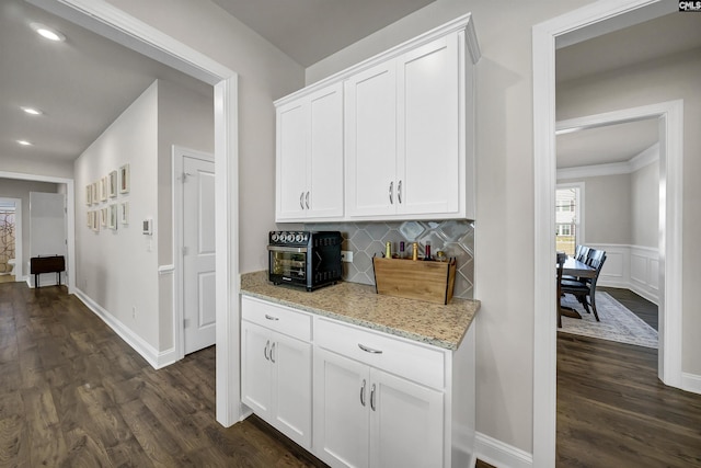 kitchen with dark hardwood / wood-style floors, light stone countertops, and white cabinets